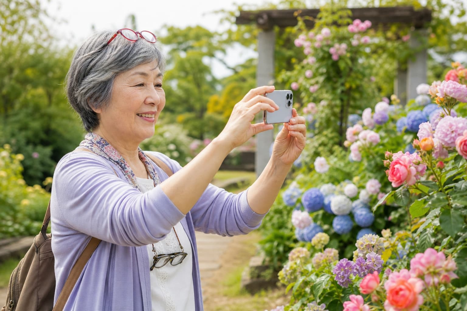 スマートフォンで庭園の花を撮影するシニア女性。NHK俳句フォト575を楽しむ初心者のイメージ。